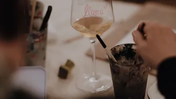 Glass with drink, hand stirring beside it.