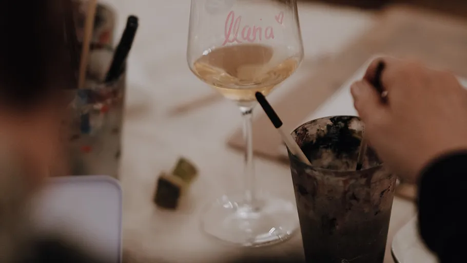 Glas mit Getränk, Hand rührt daneben.