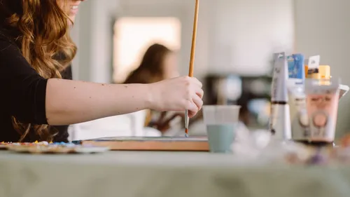 Person painting at a cluttered table.