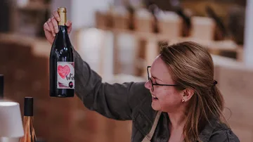 Frau hält Weinflasche, lächelt drinnen.