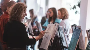 Personen malen auf Leinwänden im Studio.