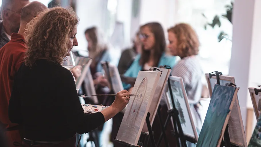 People painting on canvases in a studio.