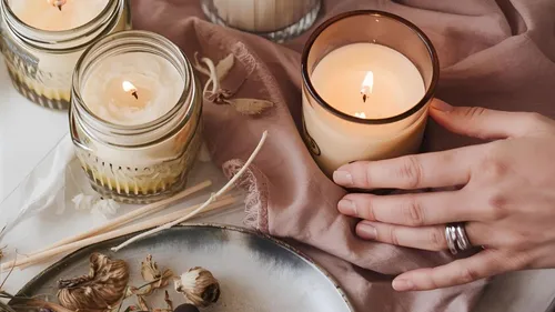 Hand holding candle on fabric surface.