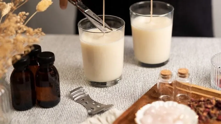 Person trimming candle wick on a table.