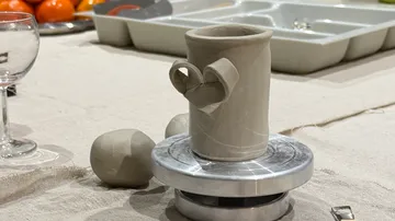 Clay mug on pottery wheel in studio.