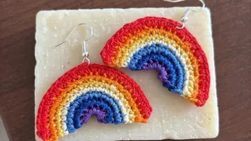 Gehäkelte Regenbogenohrringe auf Holzoberfläche.