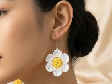 Gehäkelter Blumenohrring am Ohr einer Person.