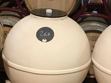 Large beige vessel amidst wooden barrels.