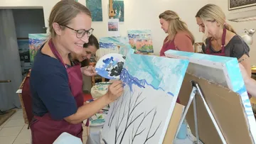 Women painting canvases in an art class.