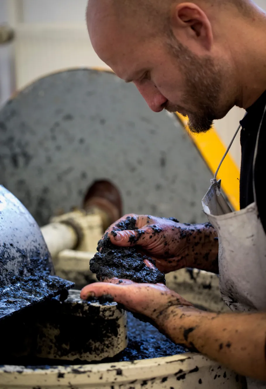 Man examining black material in industrial setting.
