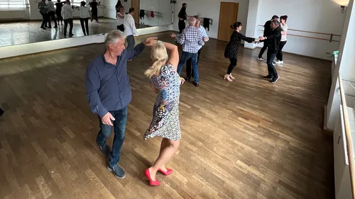Couples dancing in a wooden floor studio.