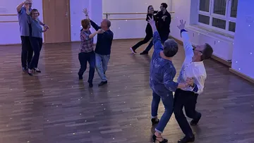Couples ballroom dancing in a studio.