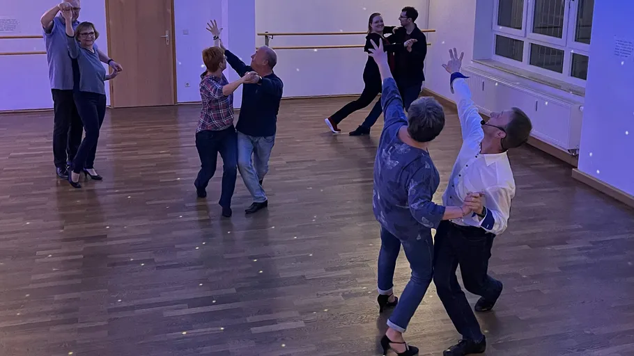 Couples ballroom dancing in a studio.