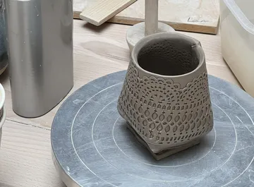 Decorated clay vessel on a pottery wheel.