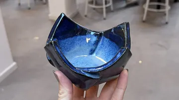 Hand hält blaue Keramikschale drinnen.