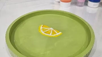 Dekorativer Teller mit Zitronenscheibe, Farben in der Nähe.