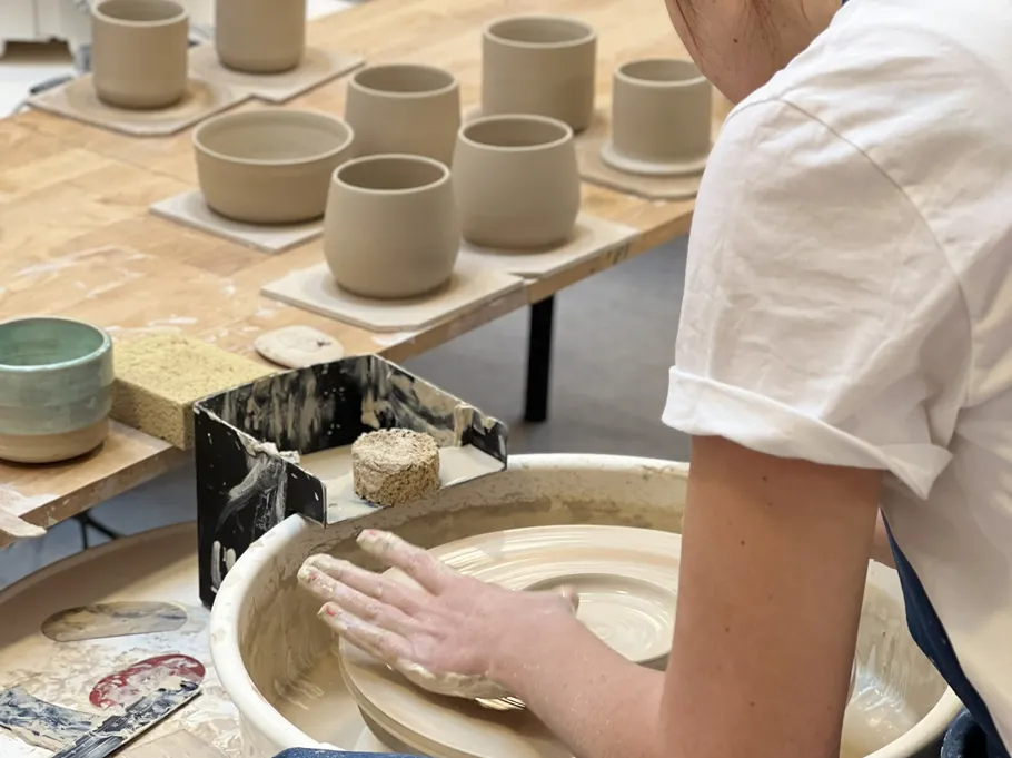 Person shaping clay on a potter's wheel.