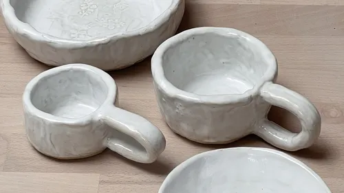 Keramikbecher und Schalen auf Holzoberfläche.
