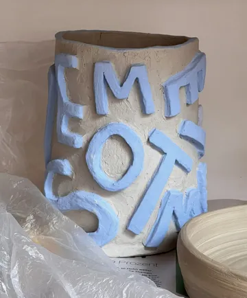 Tonvase mit blauen Buchstaben, drinnen.