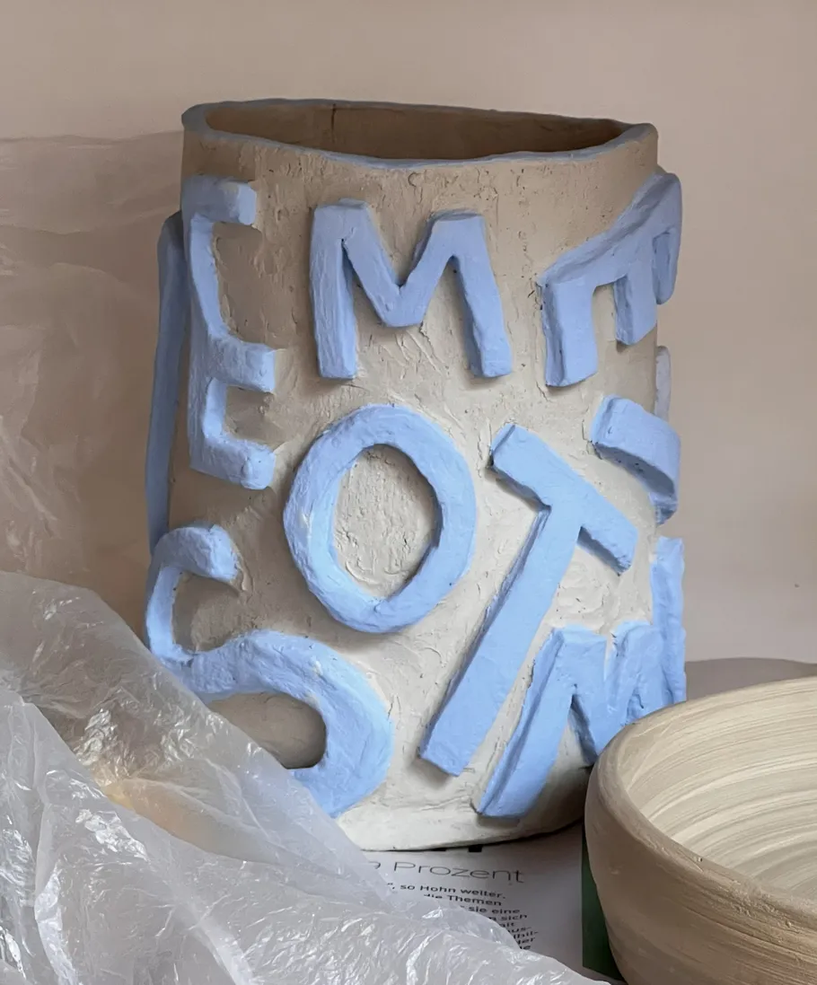 Clay vase with blue letters, indoors.