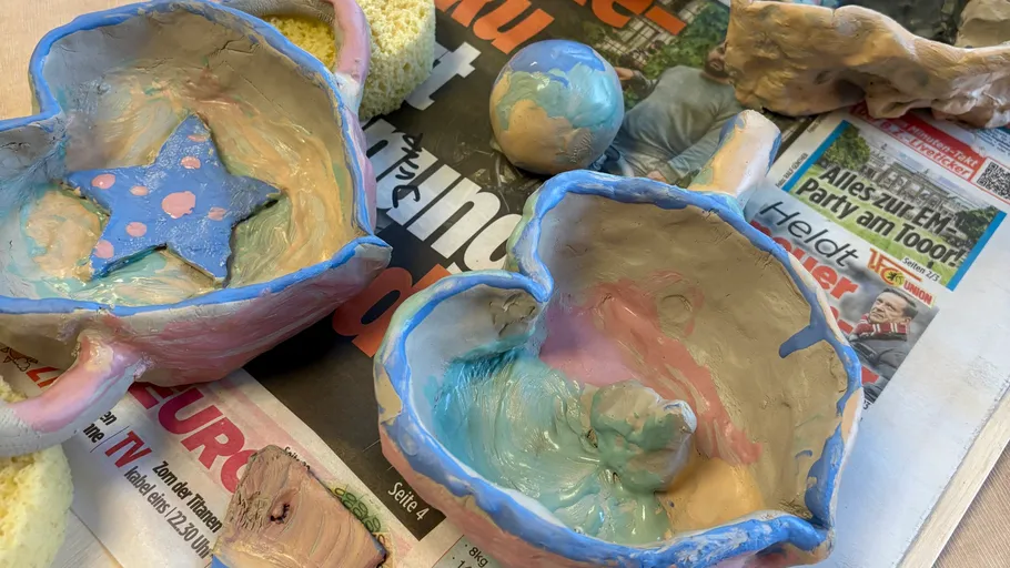 Clay pottery on newspaper, colorful designs.