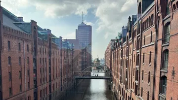 Ziegelgebäude flankieren Kanal unter Brücke.