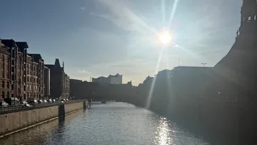 Sonne scheint über Stadtkanal und Gebäude.