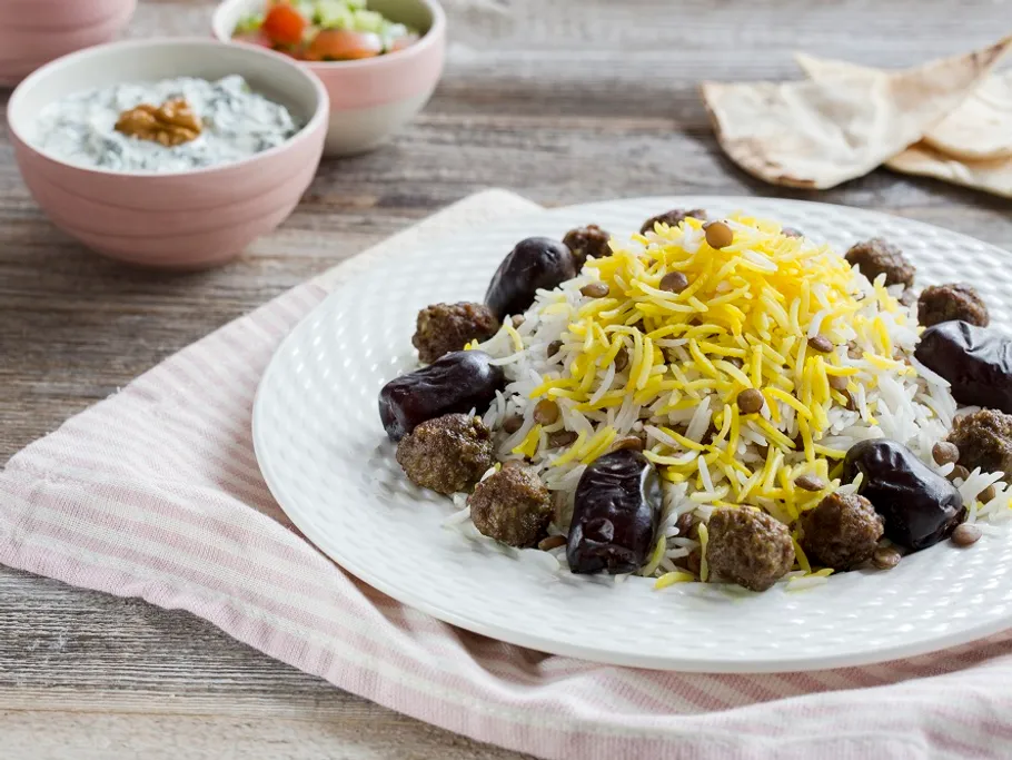 Rice dish with meatballs and dates on a plate.