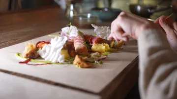 Person eating gourmet dish on table.