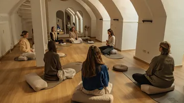 People meditating in an arched room.