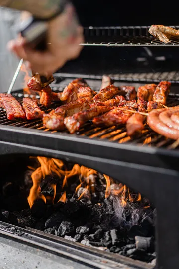 Fleisch grillt über Holzkohleflammen draußen.
