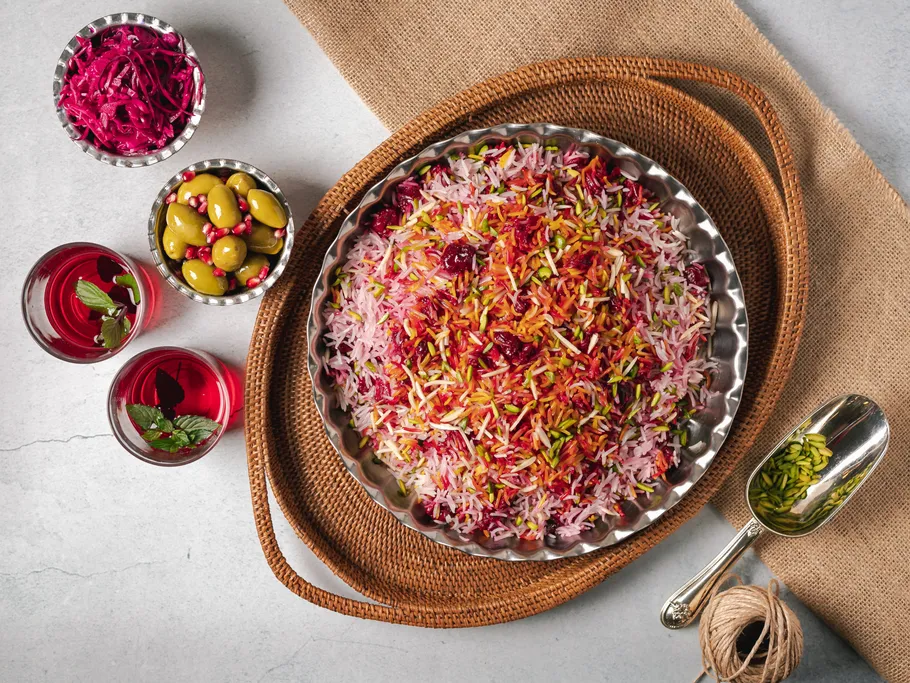 Colourful rice dish on a tray surrounded by snacks and drinks.