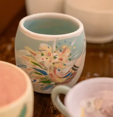 Bemaltes Keramikbecher auf Holztisch.