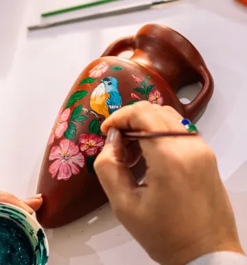 Hand painting floral design on a vase.