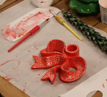 Red bow painted with brushes on table.