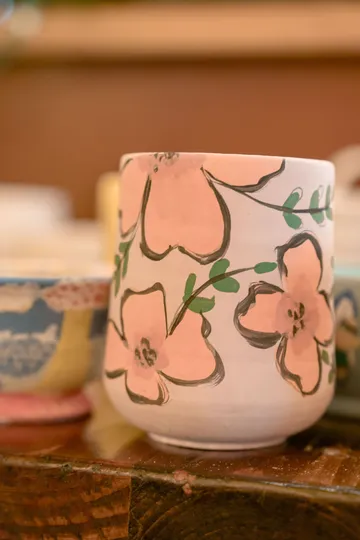 Floral-painted mug on wooden surface.