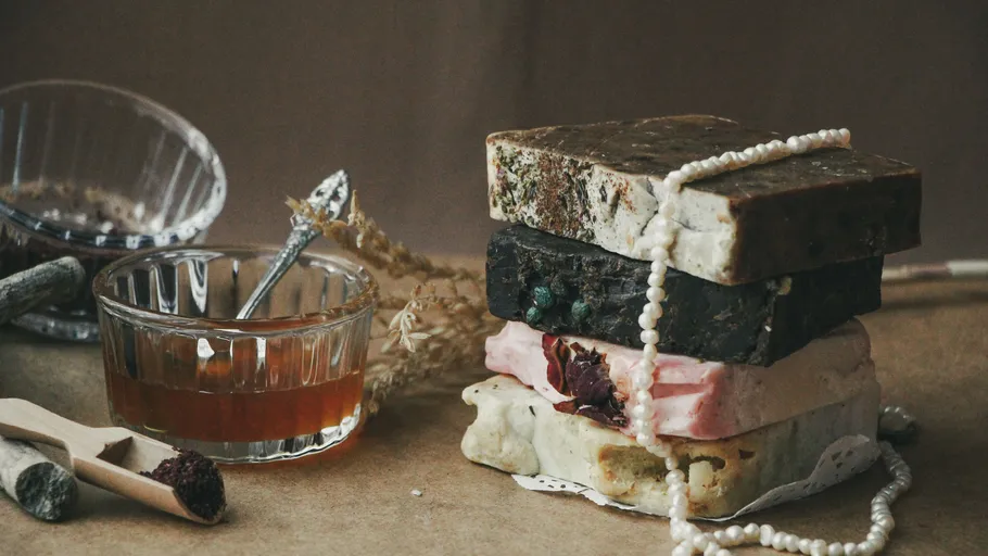 Stacked soap bars with pearl necklace, rustic setting.