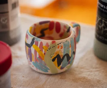 Bunter Becher mit abstraktem Design auf Tisch.