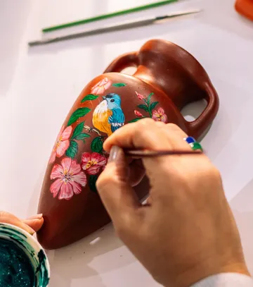 Vase mit Blumen und Vogel bemalt.