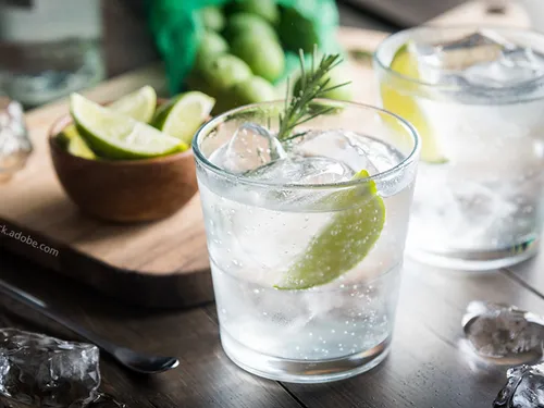Glasses with drinks, ice and limes, on a table.