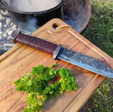Knife on cutting board with parsley outdoors.