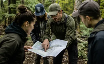 Group examines map in a forest.