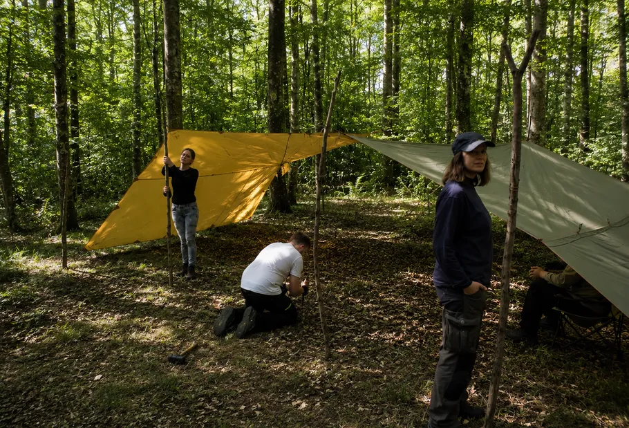 People setting up tarps in a forest.