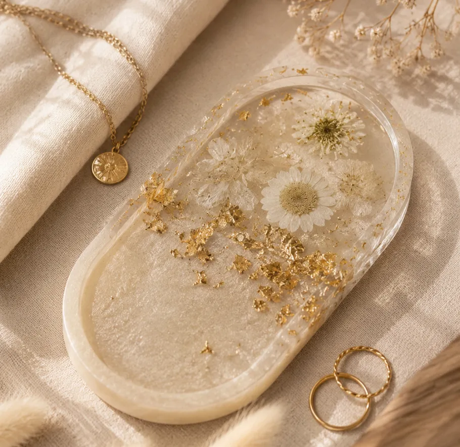 Resin tray with flowers, gold flakes, jewelry nearby.