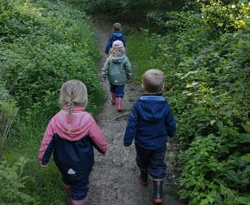 Kinder gehen auf Waldweg.