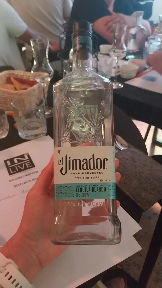 Hand hält Tequilaflasche bei Verkostung.