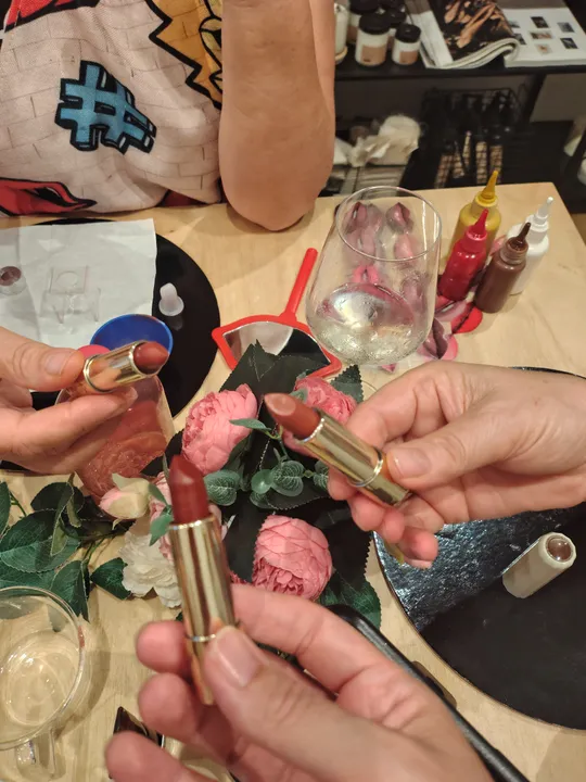 Hands holding lipsticks over a table setting.
