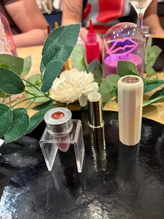 Lipstick and flowers on black tray.