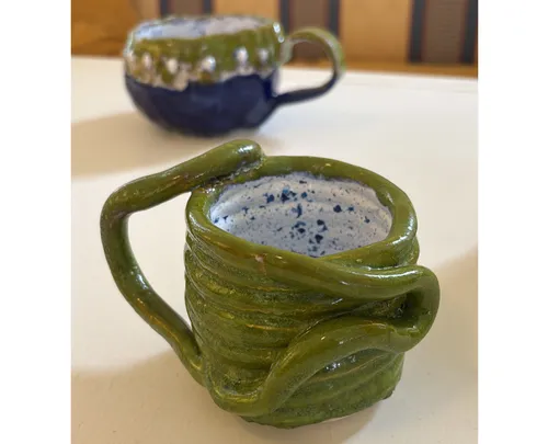 Grüne Keramiktasse mit einzigartigem Henkel-Design.