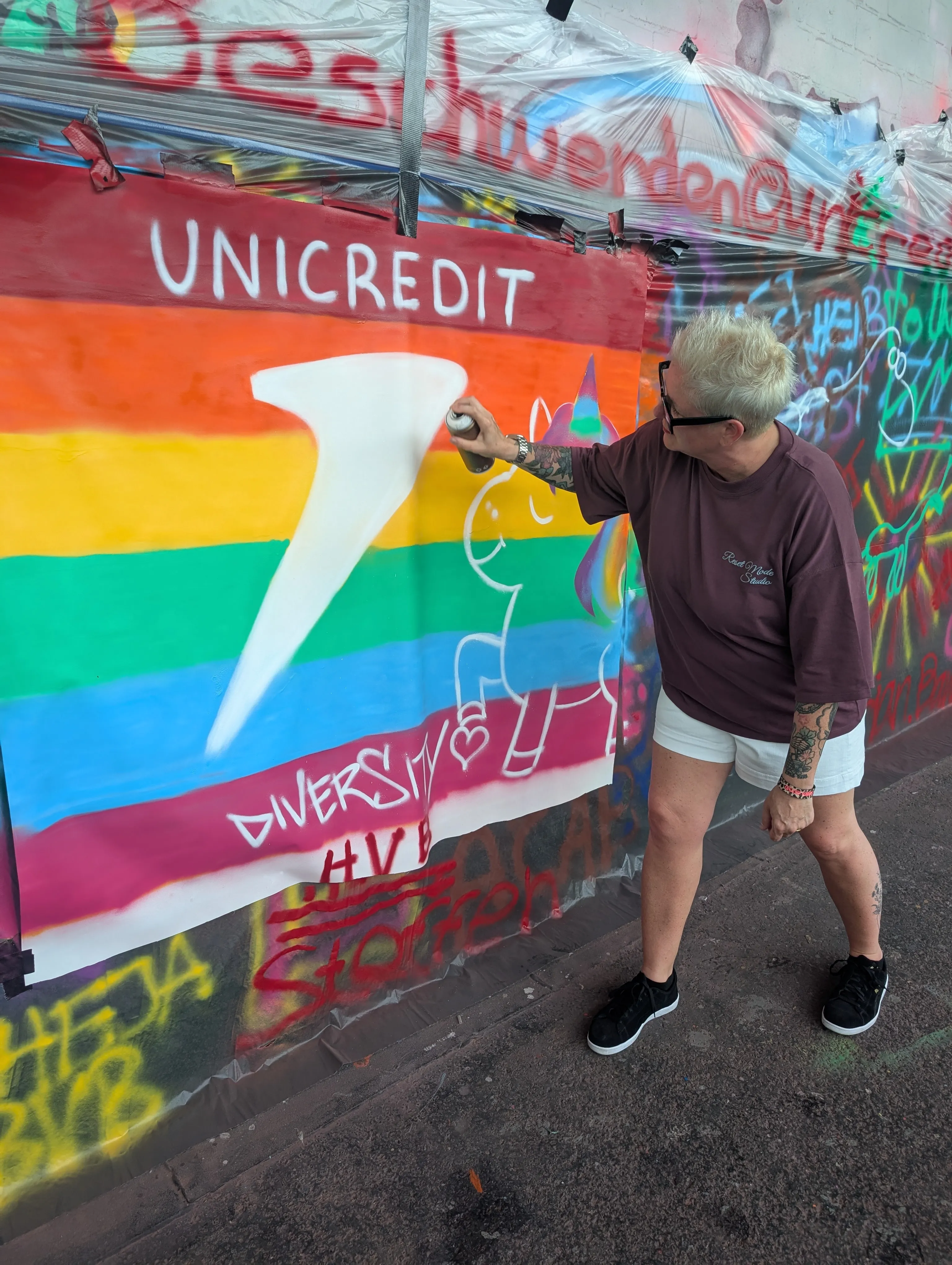Person sprüht Regenbogen-Wandgemälde an die Wand.